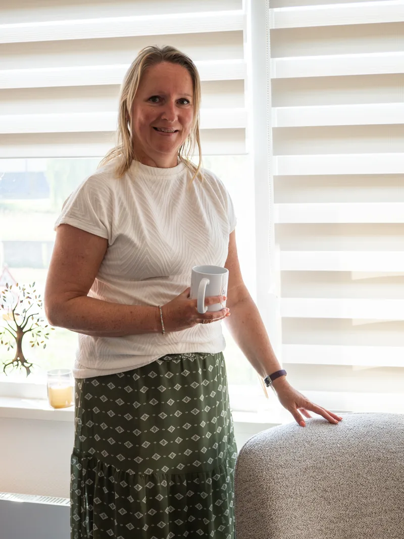 Corine Verkade met een kop thee in haar praktijk.